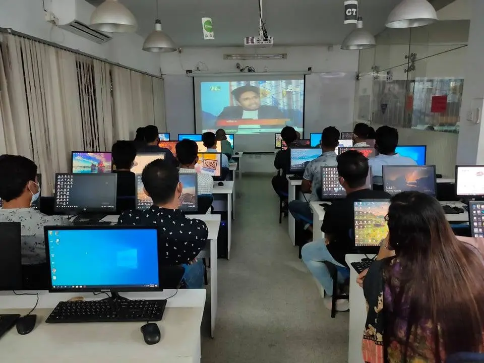 Students in an eShikhon computer classroom watching Anik Mahmud’s NTV television report through a projector in 2023.