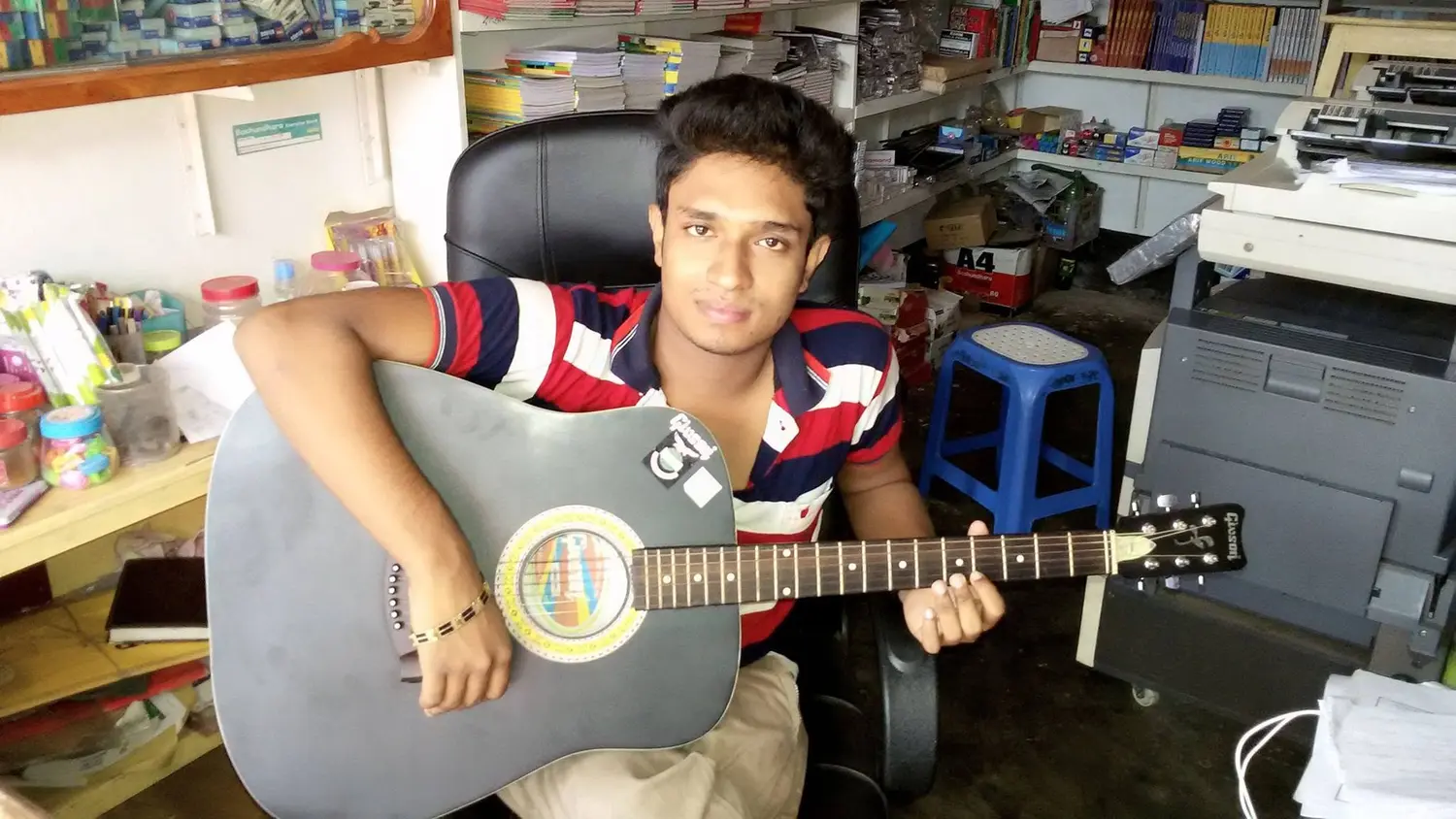 Anik Mahmud holding a guitar inside Anik Bookfair & Computers in 2015.